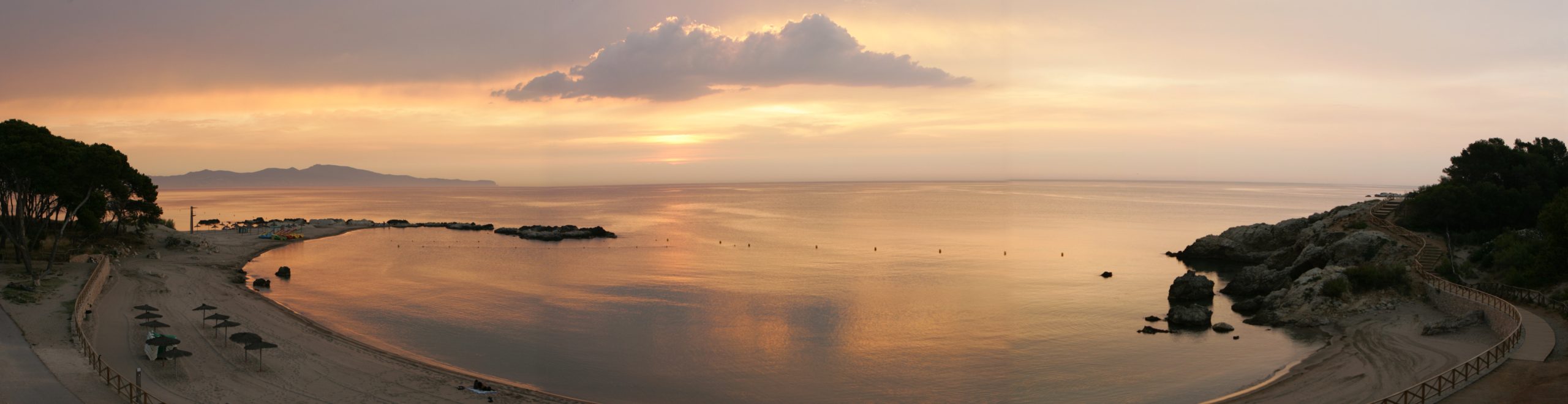 Vista panorámica de la playa y la bahía al atardecer junto a Hostal Empúries