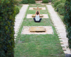 Mujer haciendo yoga en el jardín del Hostal Empúries