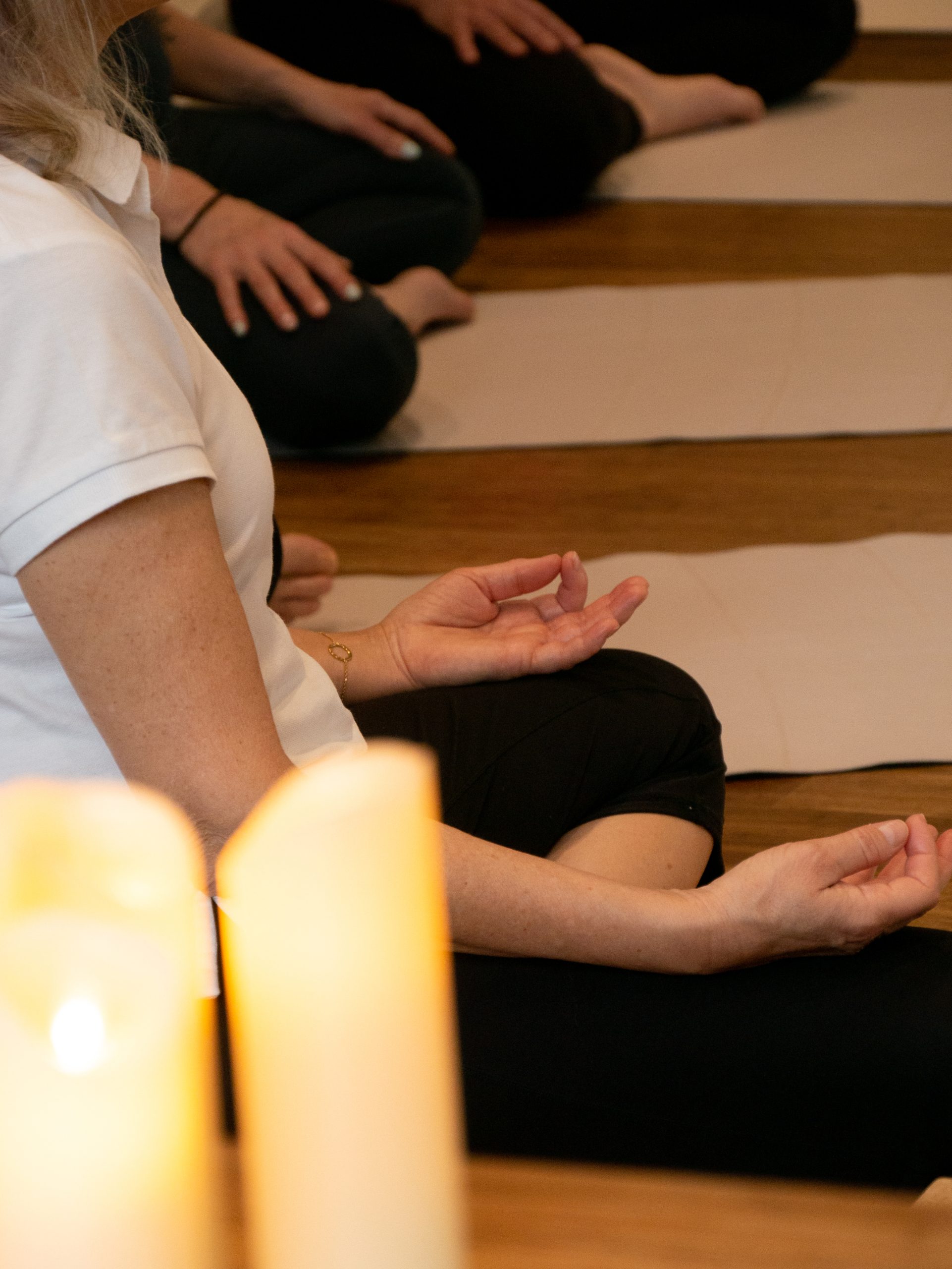 Persona meditando junto a velas encendidas en una clase de yoga en Hostal Empúries